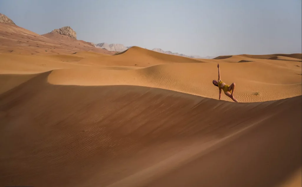 Pratique de yoga dans les dunes sous ciel bleu